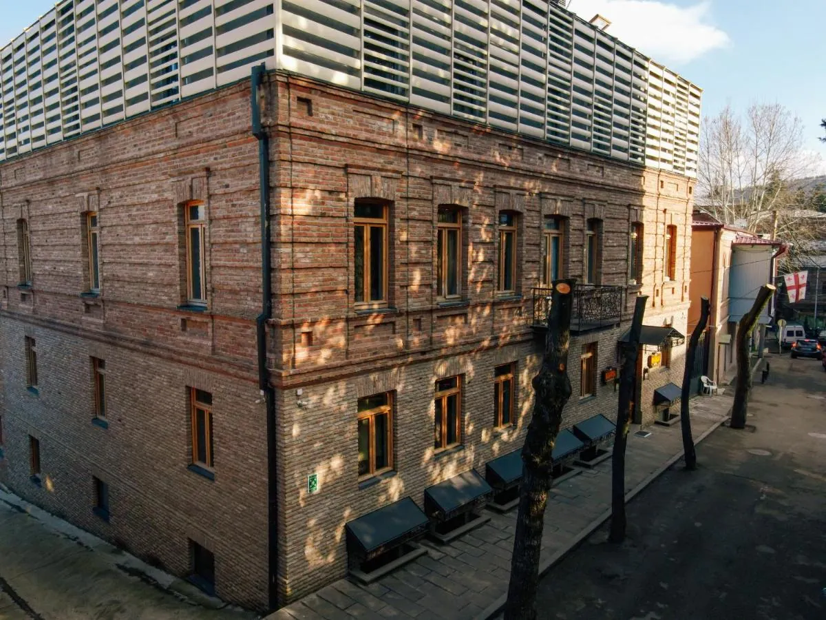 The brick facade with tall wooden windows on a quiet street