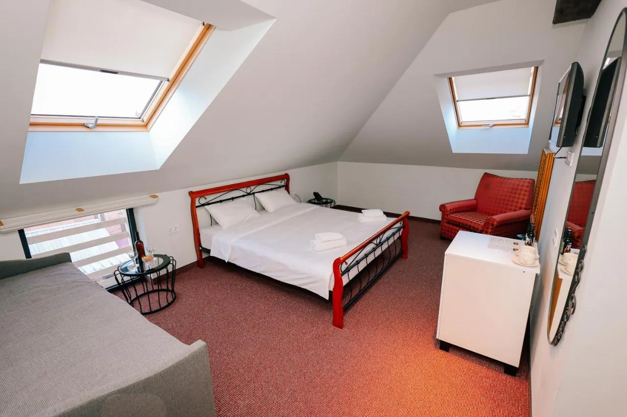 Deluxe Room with two skylights, a king bed and a red armchair