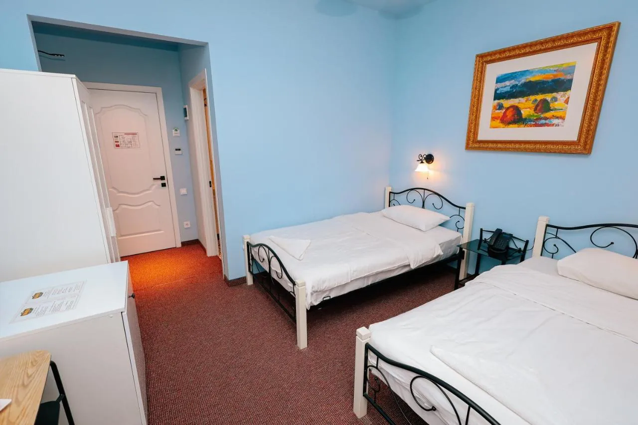 Double or Twin Room with dusty blue walls, two beds and a framed painting